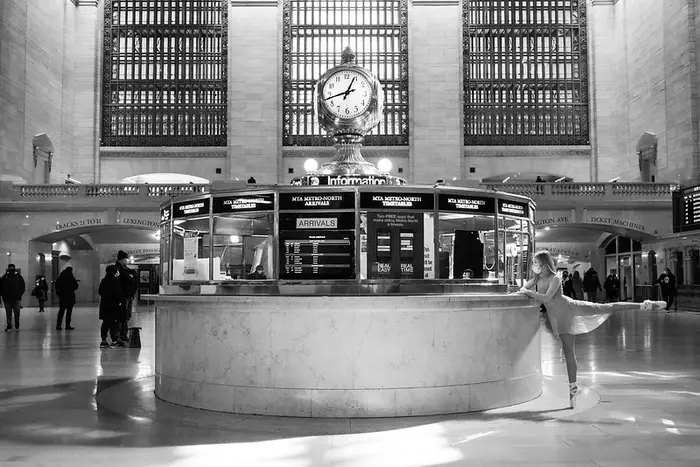 a black and white photo of a ballerina striking a pose in the middle of Grand Central